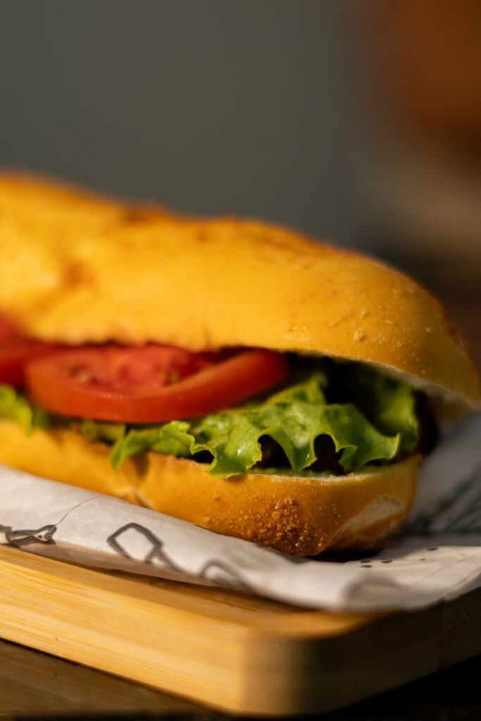 Tasty sub sandwich with fresh lettuce and tomato on a wooden board. Perfect for lunch or a casual meal.